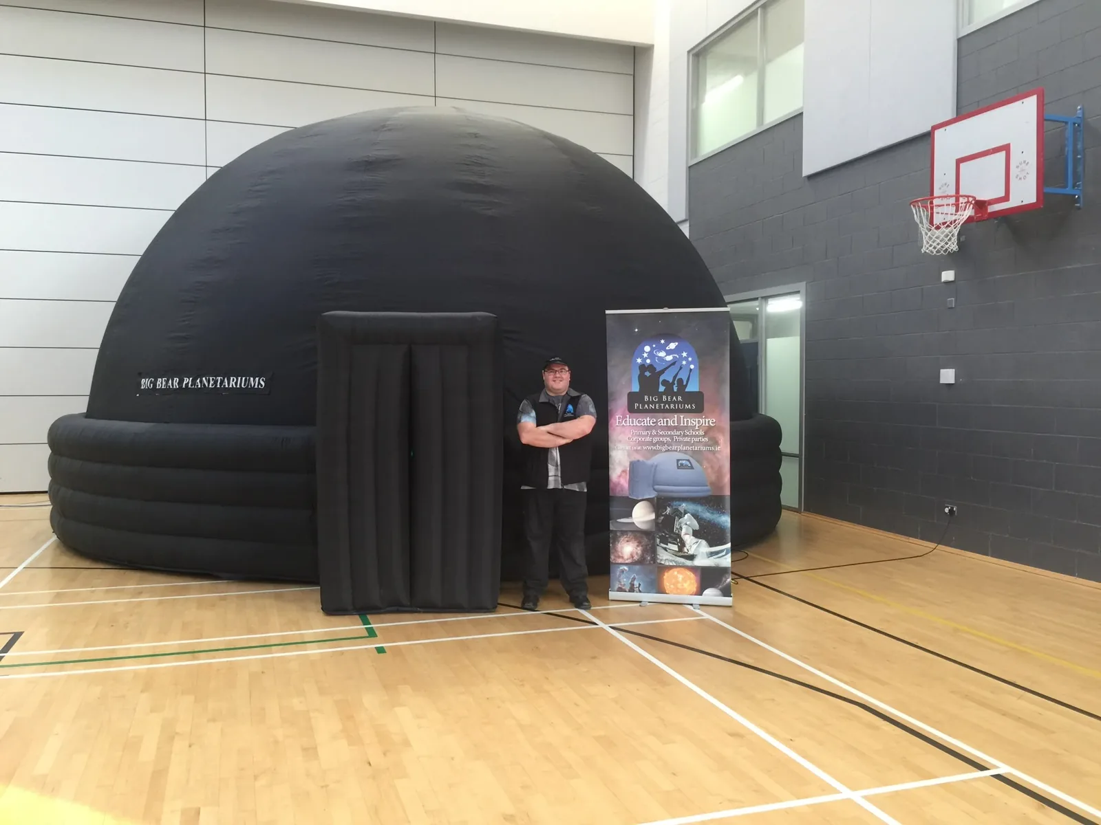 Carl O’Beirnes standing beside the Big Bear portable planetarium at a school
